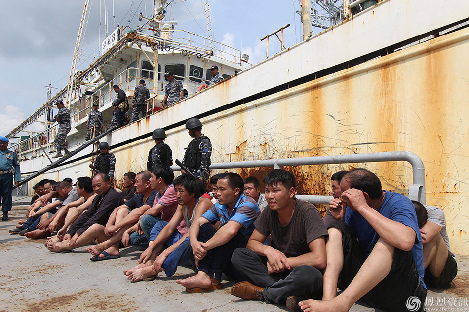 This picture taken on April 23, 2016 shows the Indonesian navy holding crew members of the Chinese trawler "Hua Li-8" in Belawan, North Sumatra. Indonesian warships have detained a Chinese trawler allegedly operating illegally in Indonesian waters, just weeks after a confrontation between vessels from the two countries caused tensions, the navy said on April 24. / AFP PHOTO / ABIMATA HASIBUAN