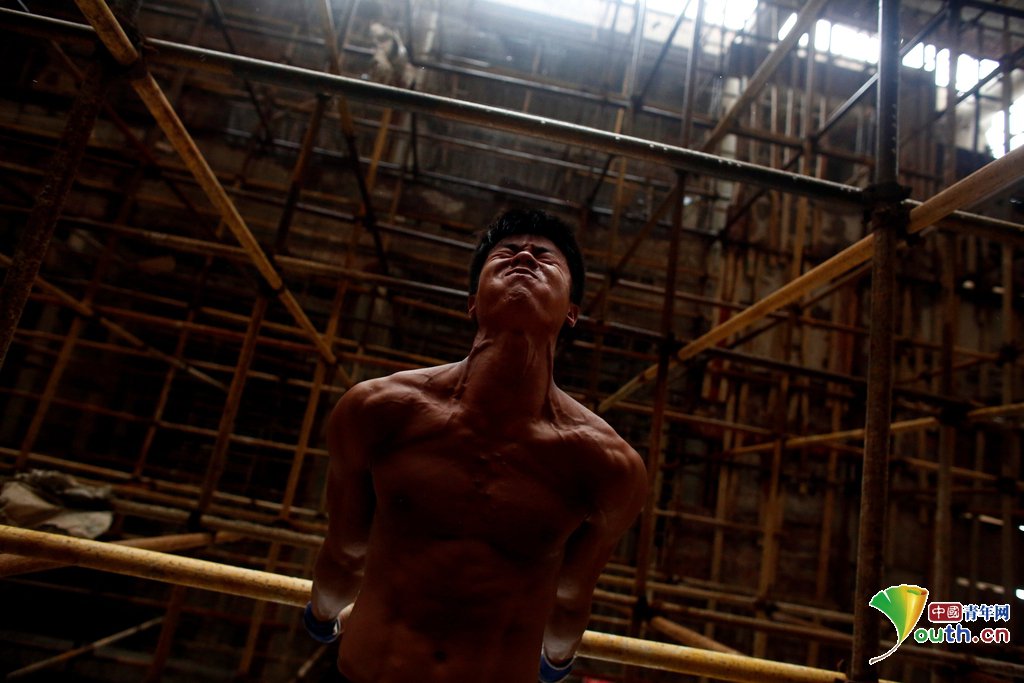 Worker Shi Shenwei performs a high bar routine on a scaffolding at the construction site of a Buddhist temple in the village of Huangshan, near Quanzhou, Fujian Province, China, September 28, 2016. REUTERS/Thomas Peter         SEARCH "BRICK CARRIER" FOR THIS STORY. SEARCH "WIDER IMAGE" FOR ALL STORIES.   TPX IMAGES OF THE DAY