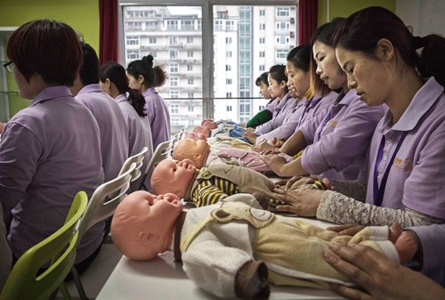 BEIJING, CHINA - OCTOBER 20:  Chinese women training to be qualified nannies, known in China as ayis, learn techniqiues with plastic babies at the Ayi University on October 20, 2016 in Beijing, China. The Ayi University training program teaches childcare, early education, housekeeping, and other domestic skills. The eight-day course costs US $250, and provides successful participants with a certificate to present to prospective employers. Most of the women attending the program are migrants from villages and cities across China who have moved to the capital to earn income to send home to their own families. China's burgeoning middle class has boosted demand for domestic help in urban areas, and the need for qualified childcare is expected to grow. In 2015, the government dismantled its controversial 'one child policy' as a means of rebalancing China's aging population in order to stave off a demographic crisis. Couples are now allowed to have two children, though the availability and cost of quality childcare is cited as an obstacle for many middle class parents who want larger families.   (Photo by Kevin Frayer/Getty Images)