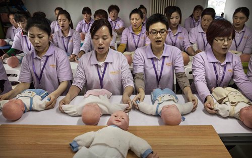 BEIJING, CHINA - OCTOBER 20:  Chinese women training to be qualified nannies, known in China as ayis, learn techniqiues with plastic babies at the Ayi University on October 20, 2016 in Beijing, China. The Ayi University training program teaches childcare, early education, housekeeping, and other domestic skills. The eight-day course costs US $250, and provides successful participants with a certificate to present to prospective employers. Most of the women attending the program are migrants from villages and cities across China who have moved to the capital to earn income to send home to their own families. China's burgeoning middle class has boosted demand for domestic help in urban areas, and the need for qualified childcare is expected to grow. In 2015, the government dismantled its controversial 'one child policy' as a means of rebalancing China's aging population in order to stave off a demographic crisis. Couples are now allowed to have two children, though the availability and cost of quality childcare is cited as an obstacle for many middle class parents who want larger families.   (Photo by Kevin Frayer/Getty Images)
