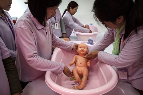 BEIJING, CHINA - OCTOBER 28: Chinese women learn bathing techniques on plastic babies at a course to train to be qualified nannies, known in China as ayis, at the Ayi University on October 28, 2016 in Beijing, China. The Ayi University training program teaches childcare, early education, housekeeping, and other domestic skills. The eight-day course costs US $250, and provides successful participants with a certificate to present to prospective employers. Most of the women attending the program are migrants from villages and cities across China who have moved to the capital to earn income to send home to their own families. China's burgeoning middle class has boosted demand for domestic help in urban areas, and the need for qualified childcare is expected to grow. In 2015, the government dismantled its controversial 'one child policy' as a means of rebalancing China's aging population in order to stave off a demographic crisis. Couples are now allowed to have two children, though the availability and cost of quality childcare is cited as an obstacle for many middle class parents who want larger families.   (Photo by Kevin Frayer/Getty Images)