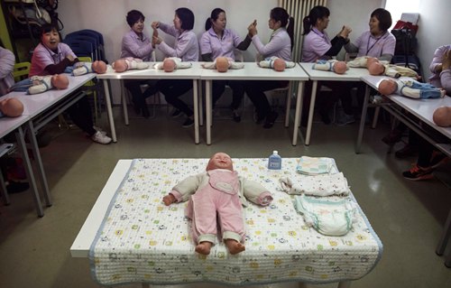 BEIJING, CHINA - OCTOBER 28: Chinese women learn techniques as they train to be qualified nannies, known in China as ayis, during a class at the Ayi University on October 28, 2016 in Beijing, China. The Ayi University training program teaches childcare, early education, housekeeping, and other domestic skills. The eight-day course costs US $250, and provides successful participants with a certificate to present to prospective employers. Most of the women attending the program are migrants from villages and cities across China who have moved to the capital to earn income to send home to their own families. China's burgeoning middle class has boosted demand for domestic help in urban areas, and the need for qualified childcare is expected to grow. In 2015, the government dismantled its controversial 'one child policy' as a means of rebalancing China's aging population in order to stave off a demographic crisis. Couples are now allowed to have two children, though the availability and cost of quality childcare is cited as an obstacle for many middle class parents who want larger families.   (Photo by Kevin Frayer/Getty Images)