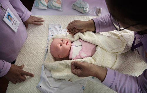 BEIJING, CHINA - OCTOBER 20:  Chinese women training to be qualified nannies learn techniqiues with a plastic baby at the Ayi University on October 20, 2016 in Beijing, China. The Ayi University training program teaches childcare, early education, housekeeping, and other domestic skills. The eight-day course costs US $250, and provides successful participants with a certificate to present to prospective employers. Most of the women attending the program are migrants from villages and cities across China who have moved to the capital to earn income to send home to their own families. China's burgeoning middle class has boosted demand for domestic help in urban areas, and the need for qualified childcare is expected to grow. In 2015, the government dismantled its controversial 'one child policy' as a means of rebalancing China's aging population in order to stave off a demographic crisis. Couples are now allowed to have two children, though the availability and cost of quality childcare is cited as an obstacle for many middle class parents who want larger families.   (Photo by Kevin Frayer/Getty Images)