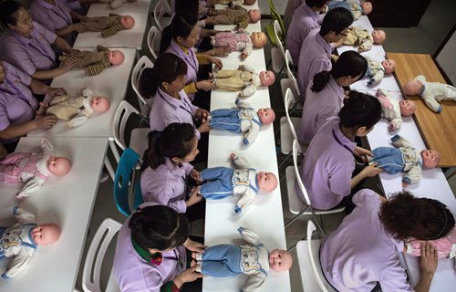 BEIJING, CHINA - OCTOBER 20:  Chinese women training to be qualified nannies, known in China as ayis, learn techniqiues with plastic babies at the Ayi University on October 20, 2016 in Beijing, China. The Ayi University training program teaches childcare, early education, housekeeping, and other domestic skills. The eight-day course costs US $250, and provides successful participants with a certificate to present to prospective employers. Most of the women attending the program are migrants from villages and cities across China who have moved to the capital to earn income to send home to their own families. China's burgeoning middle class has boosted demand for domestic help in urban areas, and the need for qualified childcare is expected to grow. In 2015, the government dismantled its controversial 'one child policy' as a means of rebalancing China's aging population in order to stave off a demographic crisis. Couples are now allowed to have two children, though the availability and cost of quality childcare is cited as an obstacle for many middle class parents who want larger families.   (Photo by Kevin Frayer/Getty Images)