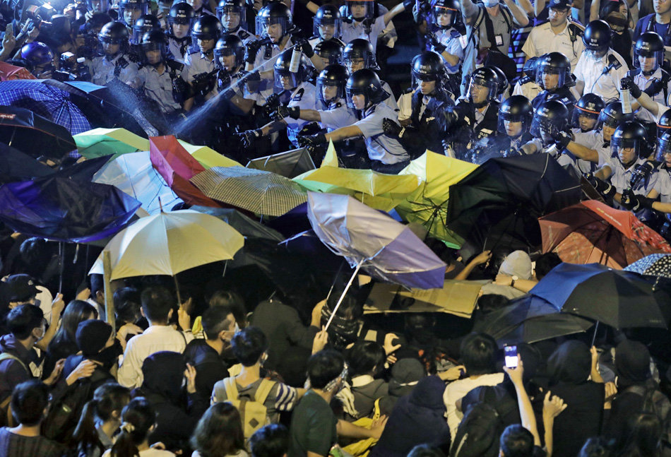 Protesters use umbrellas to block the pepper spray from office officers after clashing as thousands of people march in a Hong Kong down town street, Sunday, Nov. 6, 2016, to protest China's top legislative panel has said Beijing must intervene in a Hong Kong political dispute to deter advocates of independence for the city, calling such acts a threat to national security. (AP Photo/Vincent Yu)